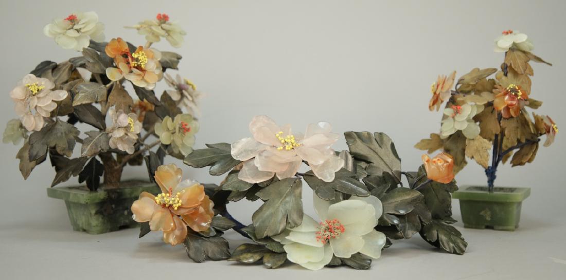 Collection of Asian Soapstone Floral Arrangements: Collection of Asian Soapstone Floral Arrangements. This lot includes two soapstone and hardstone floral arrangements and one centerpiece. Hand Carved bonsai form. Largest piece measures 11 inches x 11