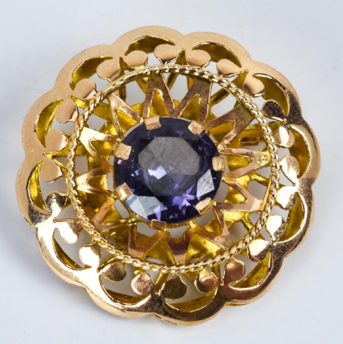14K Gold and Alexandrite Brooch: 14K Gold and Alexandrite Brooch. Brooch features a centered Alexandrite stone. 2.8 DWT inclusive of stone. 1.25 inches in diameter.