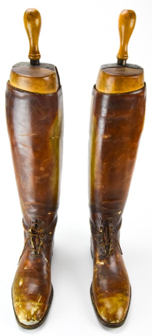 Pair Leather Riding Boots W Boot Stretchers: Pair Leather Riding Boots W Boot Stretchers. This lot features a pair of leather riding boots with wooden boot stretchers inside. 24 inches x 12 inches x 4 inches.