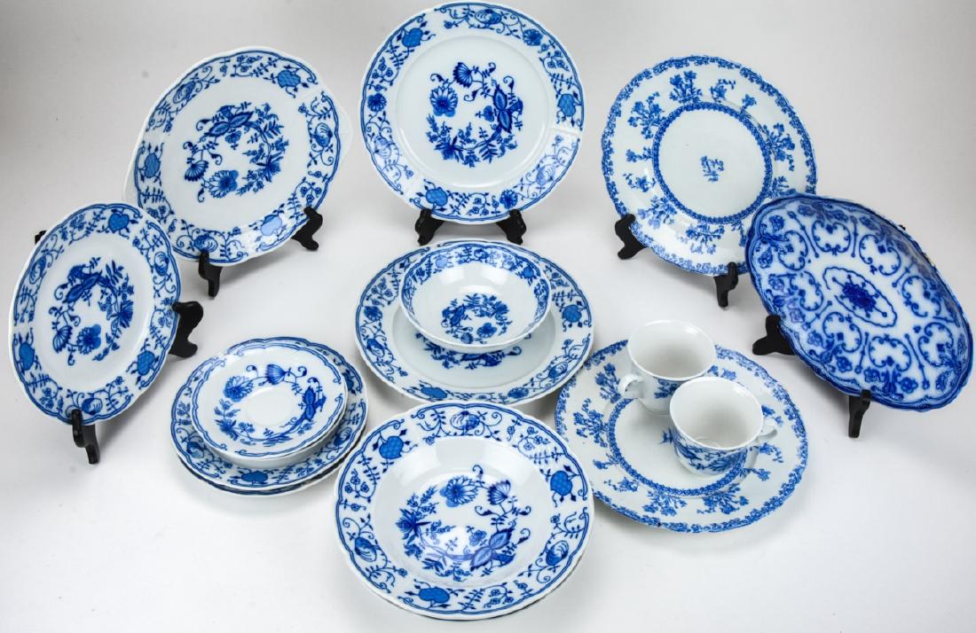 Lot of Flow Blue Style Serve Ware Pieces: Lot of Flow Blue Style Serve Ware Pieces. This lot features a collection of flow blue style porcelain plates, cups, and serveware of mixed makers and styles. Largest piece measures 10 inches in diamet
