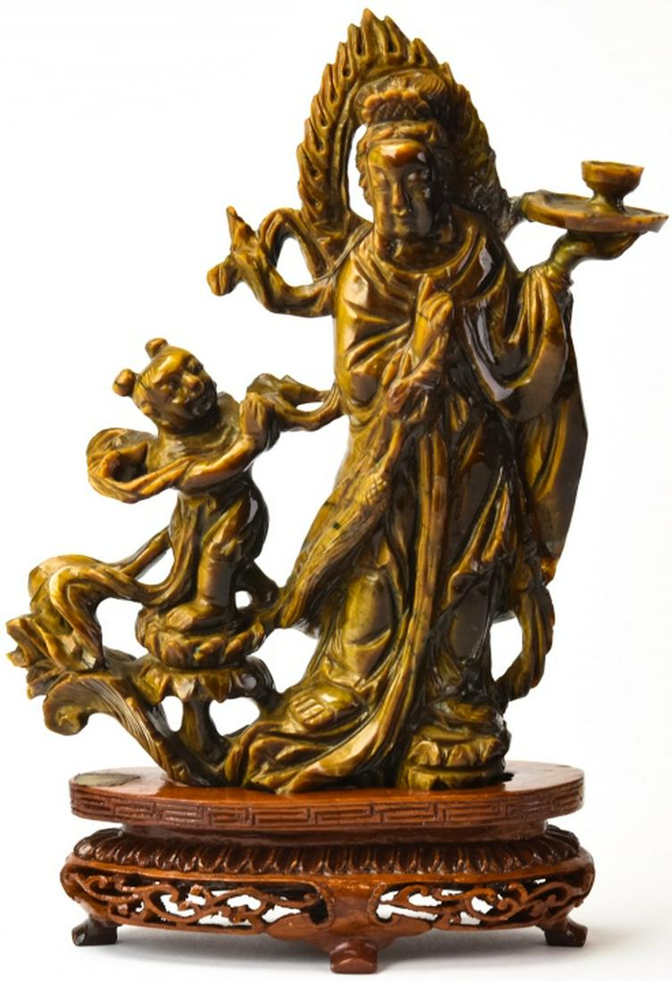 Chinese Hand Carved Tigers Eye Figural Statue: Chinese Hand Carved Tigers Eye Figural Statue. Hand carved figural statue depicting a goddess with a child. Tests as jadeite on the presidium. Statue measures 6.5 inches x 5 inches x 1 inch without st