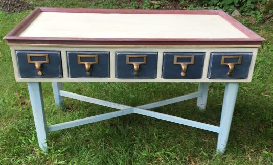 Hand Painted Library Card Catalog Coffee Table: Hand Painted Library Card Catalog Coffee Table. Faux library card catalog coffee table (drawers do not open). Hand painted in red, white and blue colors. 21 inches x 34 inches x 20 inches.