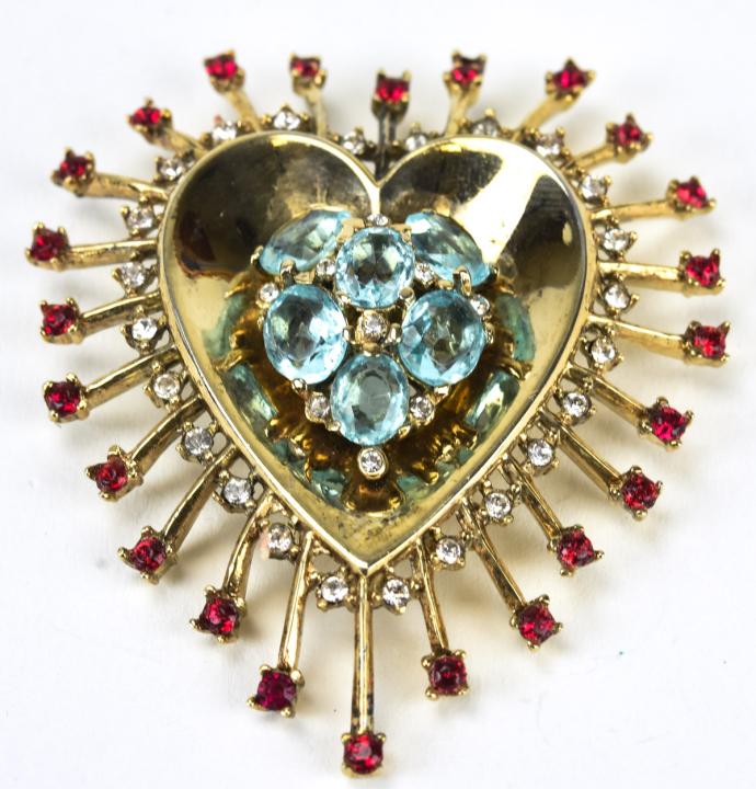 Trifari Circa 1945 Sterling Heart Brooch / Clip: Trifari Circa 1945 Sterling Heart Brooch / Clip. Trifari crown heart brooch in sterling with aqua, ruby and clear paste. Measures 2.25 inches x 1 7/8 inches. Hallmarked on back.