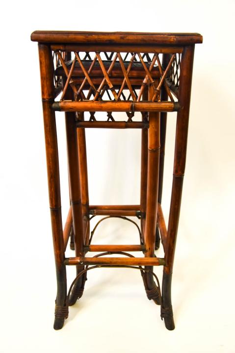 2 Plantation Style Faux Bamboo Nesting Tables: 2 Plantation Style Faux Bamboo Nesting Tables / Pedestals. Each with rattan tops. Larger measures 31.5 inches x 14 inches x 14 inches.