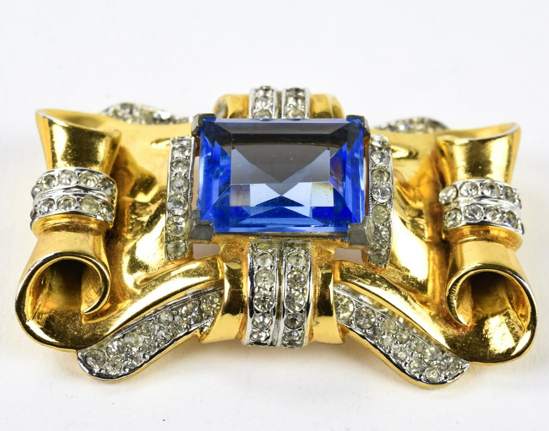 C 1940 Coro Scrolled Gilt & Crystal Retro Brooch: C 1940 Coro Scrolled Gilt & Crystal Retro Brooch. Bold signed Coro blue crystal in scrolled gilt setting with clear paste design brooch. Measures 2.25 inches in width.