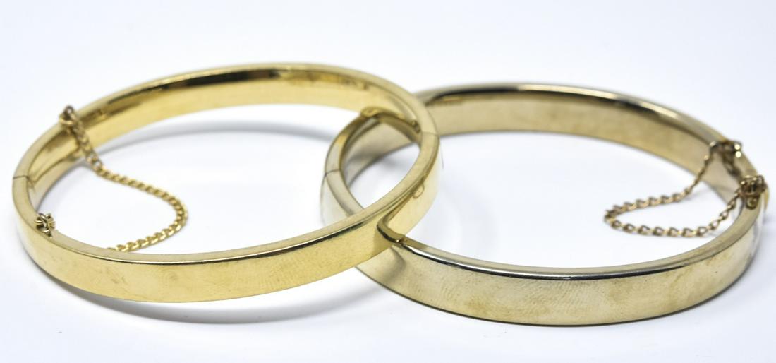 Two Estate Gold Filled Hinged Bangle Bracelets: Two Estate Gold Filled Hinged Bangle Bracelets. High shine finish with safety chains. Made by Ballou. Total weight 26.4 grams. Larger measures just over 2.25 inches across interior opening.