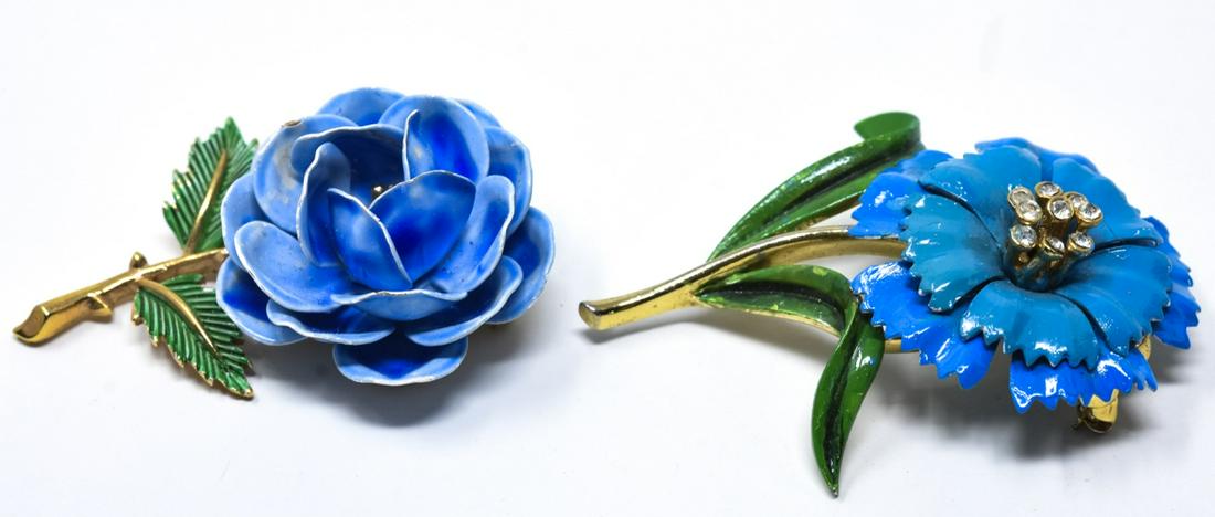 C 1970 2 Trifari Blue Flower Pins / Brooches: C 1970 2 Trifari Blue Flower Pins / Brooches. Two Trifari blue flwers with green leaves in gilt fittings with clear paste. Larger measures nearly 2.5 inches.