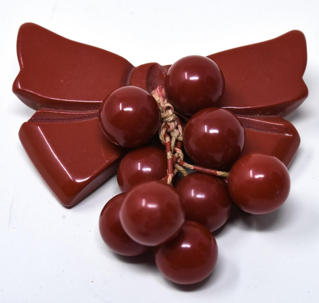 Red Chunky Bakelite Carved Ribbon Bow Brooch / Pin: Red Chunky Bakelite Carved Ribbon Bow Brooch / Pin. With cherry center cluster. Measures 2.5 inches x 2.5 inches.