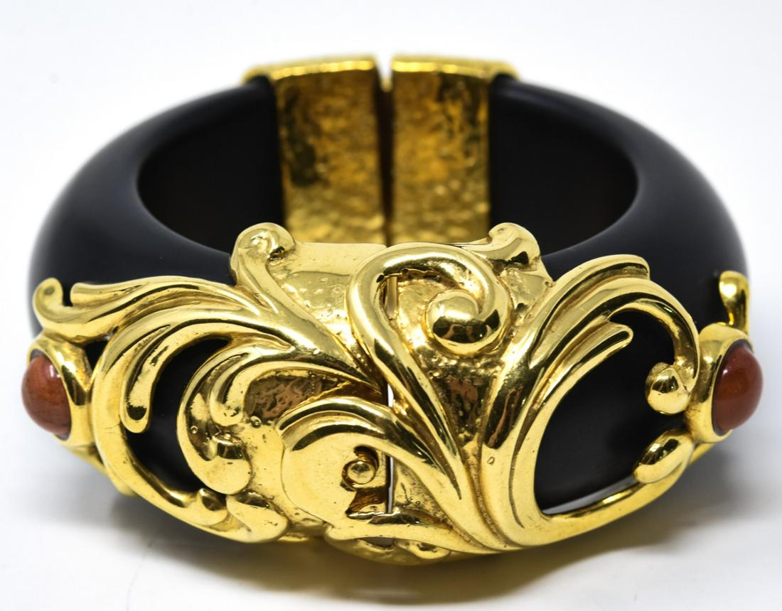Inna Cytrine Paris Black Acrylic Bangle Bracelet: Inna Cytrine Paris Black Acrylic Bangle Bracelet. With gilt Rococo swirl design and faux coral cabochons. With push button catch. Unsigned. Measures 2.25 inches across the interior opening.