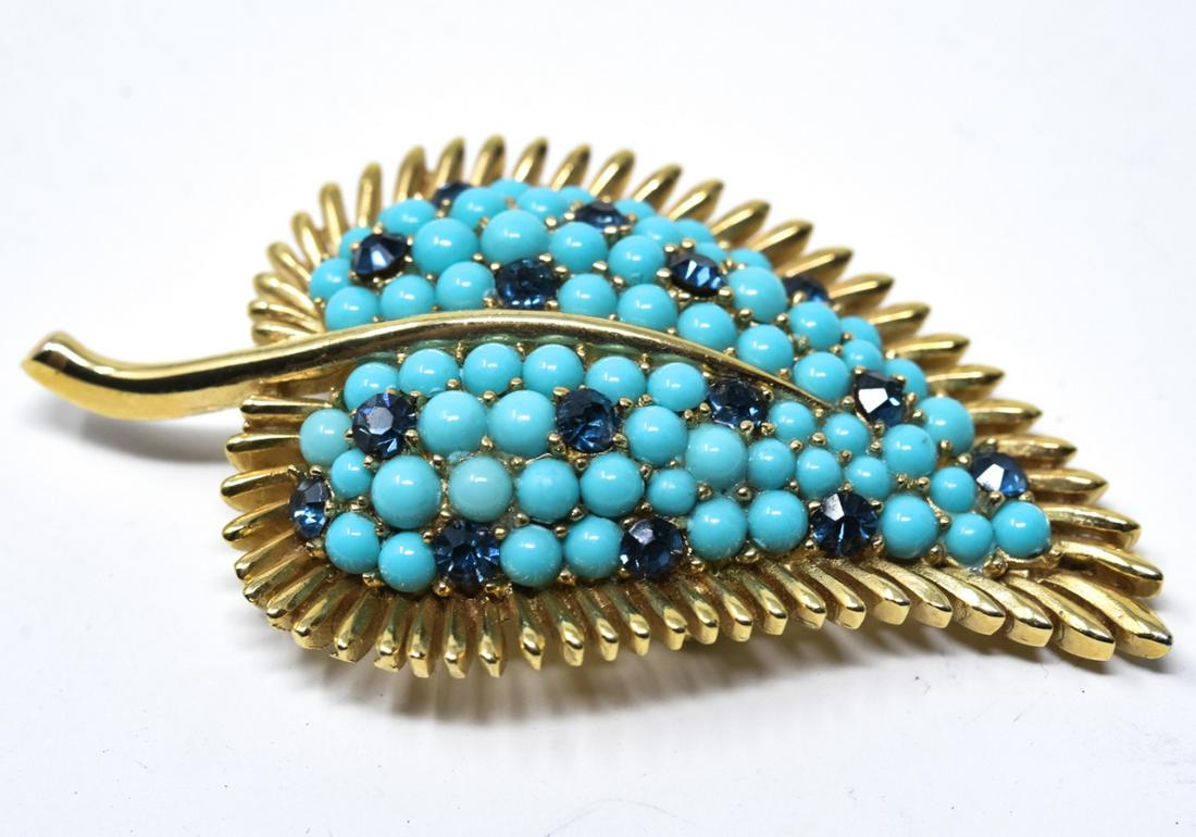 C 1970 Crown Trifari Gilt Leaf Brooch / Pin: C 1970 Crown Trifari Gilt Leaf Brooch / Pin. With pave turquoise cabochons and sapphire paste center. Measures 2.25 inches in width.
