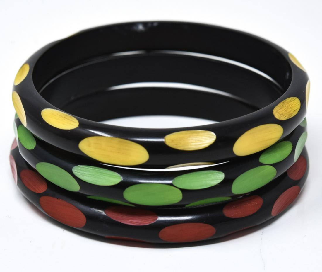 C 1960s 3 Black Bakelite Bangle Bracelets: C 1960s 3 Black Bakelite Bangle Bracelets. Bakelite black overdye cut to red, green and yellow. Each measures 2.5 inches across the interior opening.