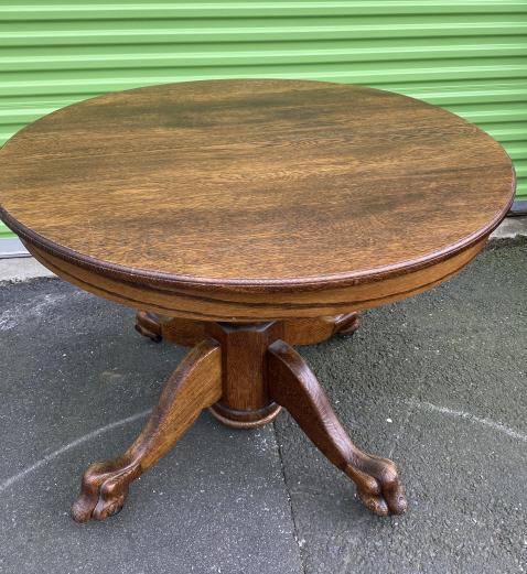 Carved Oak Footed Round Pedestal Dining Table: Carved Oak Lion's Paw Footed Round Pedestal Dining Table. Measures 29 inches in height by 41.75 in diameter.