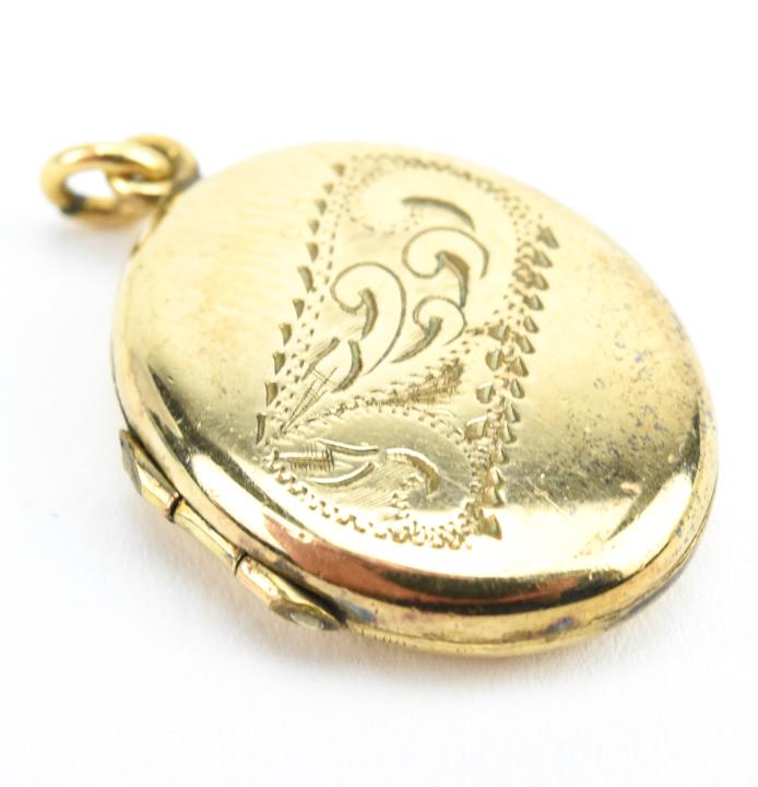 Antique Gold Scrollwork Motif Locket Pendant: Antique Gold Scrollwork Motif Locket Pendant. Gold filled locket necklace pendant with scrollwork ribbon design on front. Measures just under 1.25 inches in length.