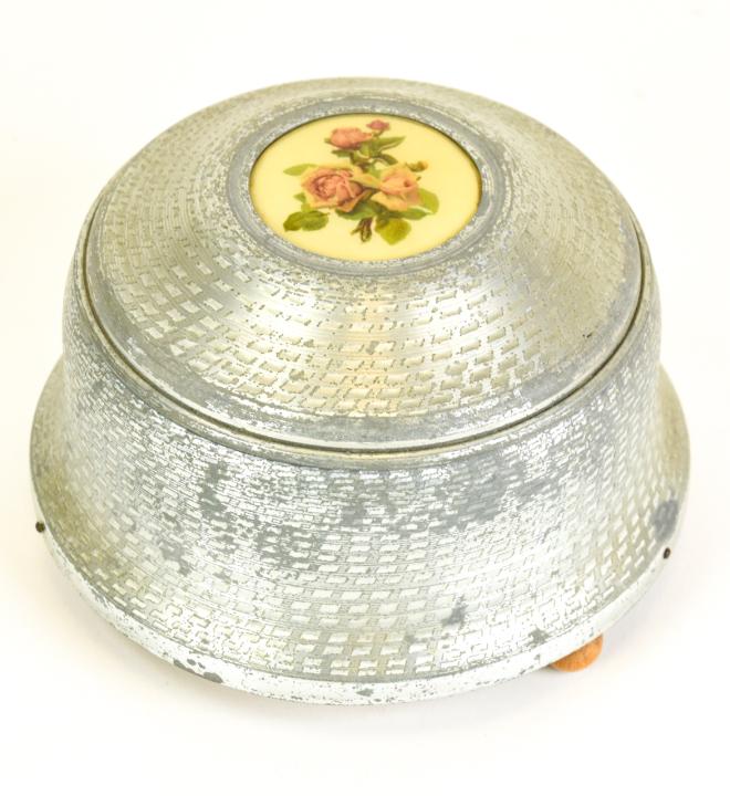 Vintage Aluminum Vanity Powder Music Box: Vintage Aluminum Vanity Powder Music Box with Rose Medallion. The winding music component is functioning. 4 inches x 5.5 inches in diameter.