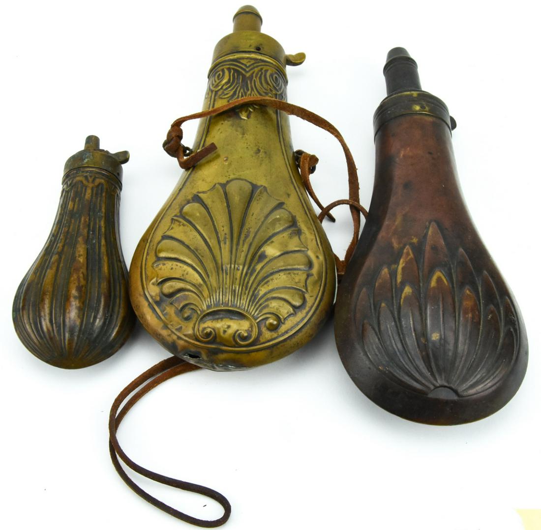 Antique Embossed Brass & Copper Gun Powder Flasks: Lot 3 Antique Embossed Brass & Copper Gun Powder Flasks. Flasks feature acanthus, floral, and fluted designs respectively. Largest measures 8 inches high x 3.5 inches wide x 1 inch deep.