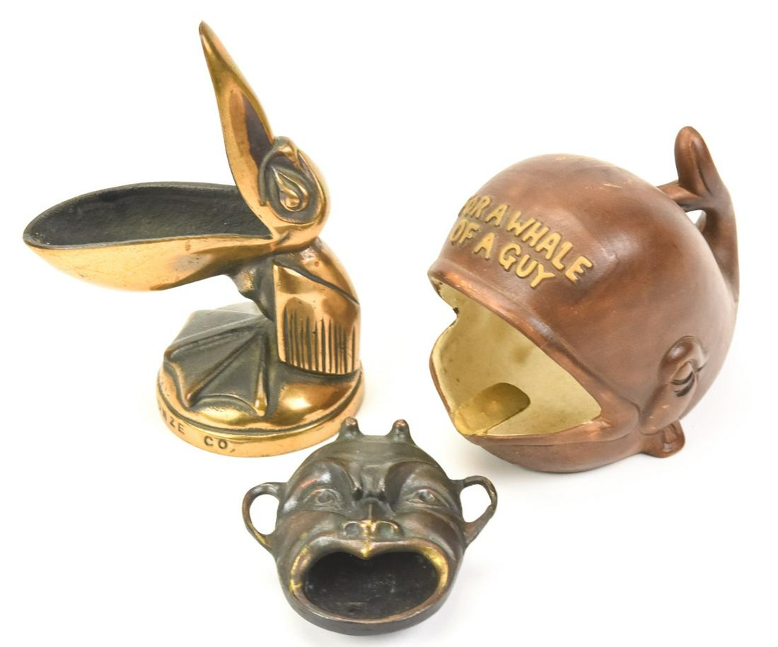 Three Vintage Cigar / Cigarette Ashtrays: Three Vintage Cigar / Cigarette Ashtrays. Includes, Johnson Bronze Co Pelican, Chinese mask, & a whale. Pelican 5.50 inches x 3 inches.
