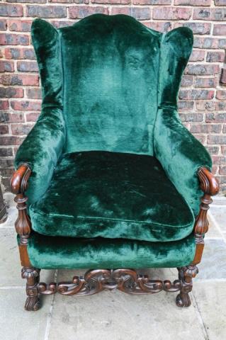 Jacobean Carved Velvet Upholstered Wingback Chair: Jacobean Style Heavily Carved Velvet Upholstered Wingback Chair. Featuring carved scrolled arms, carved stretcher with block and turned and blocked construction, ending in Spanish feet. Measures 43.5 