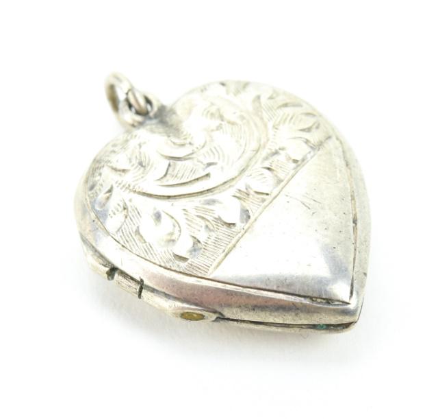10Antique Sterling Silver Heart Locket Pendant: Antique Sterling Silver Heart Locket Necklace Pendant Having chaste scroll work design on front, back is harllmarked. Measures 1 inch in length.
