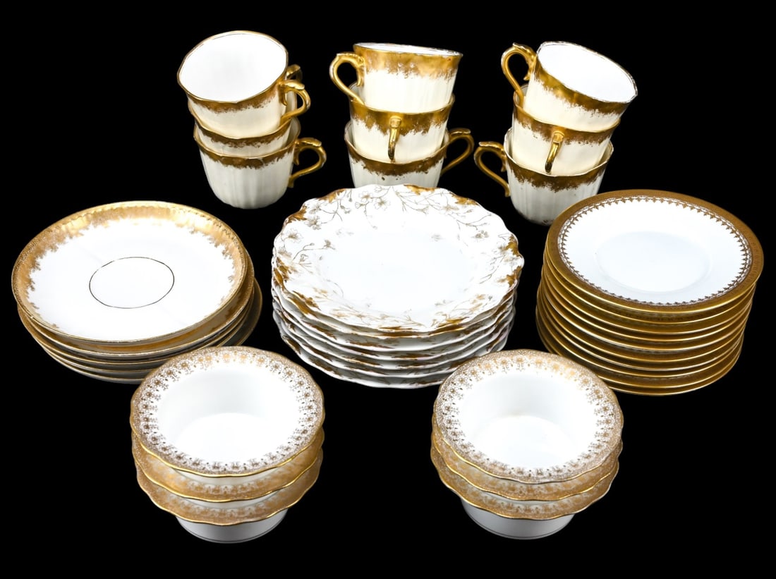 Collection Antique Limoges Gold White Dishes: Collection Antique Limoges Gold White Dishes that includes as assortment of pudding dishes, cake plates, coffee cups, and saucers. There is some gold paint loss. In an assortment of styles and sizes. 