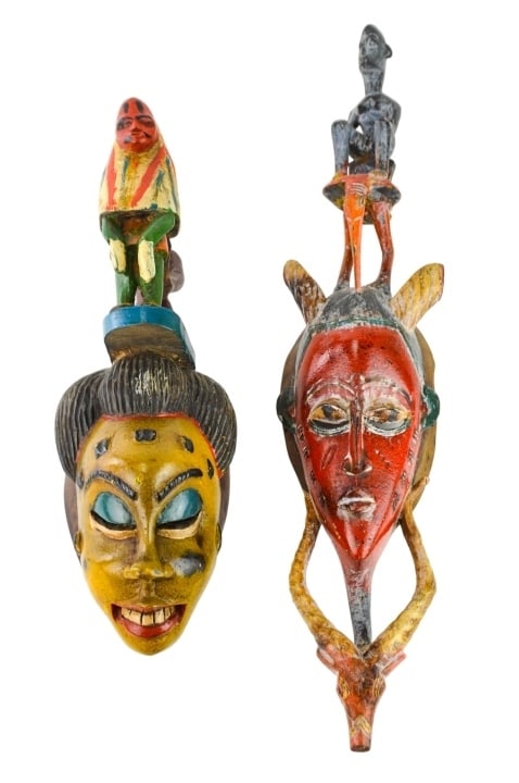 2 African Guro Ivory Coast Hand Carved Masks: 2 African Guro Ivory Coast Hand Carved and Hand Painted Polychrome Masks with Carved Figural Finials. Longer measures 28 inches x 7 inches