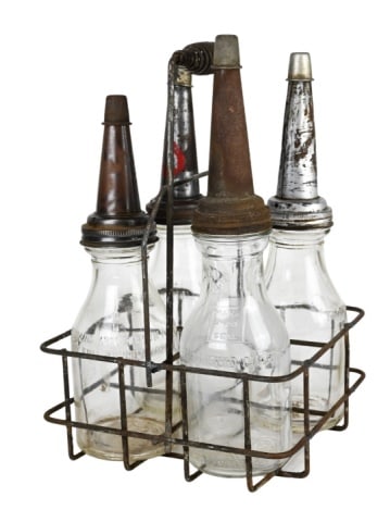 Antique Motor Oil Bottles in Steel Wire Carry Rack: 4 Antique Glass Motor Oil Bottles w Covers with Spouts in Steel Carry Rack. Together measure 16 inches x 10 inches x 10 inches.