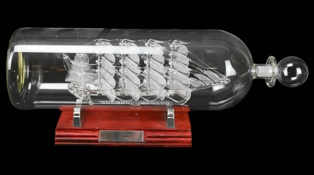 Hand Blown Art Glass Clipper Ship in Glass Bottle: Hand Blown Art Glass Clipper Ship in Glass Bottle. Measures 6 inches x 14 inches on stand.