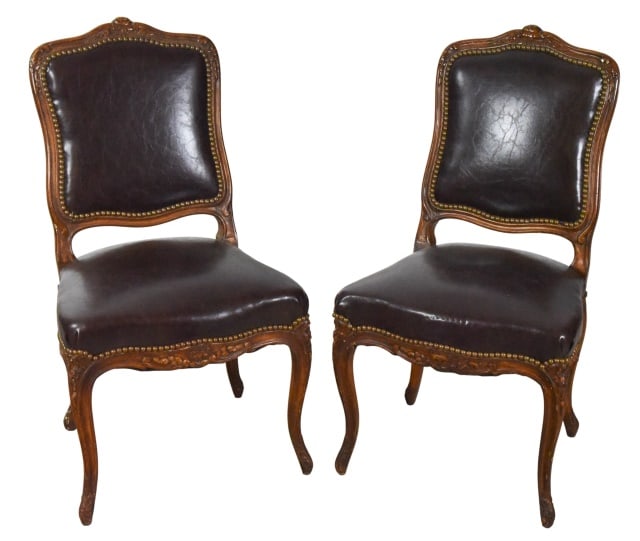 Pair Antique Carved Leather Upholstered Chairs: Pair Antique Hand Carved Leather Custom Upholstered Chairs with nail Head Trim. Needs refurbishment. One leg shows signs of repair. Sold as is.Measures 36 inches x 20 inches x 18 inches, seat height 1