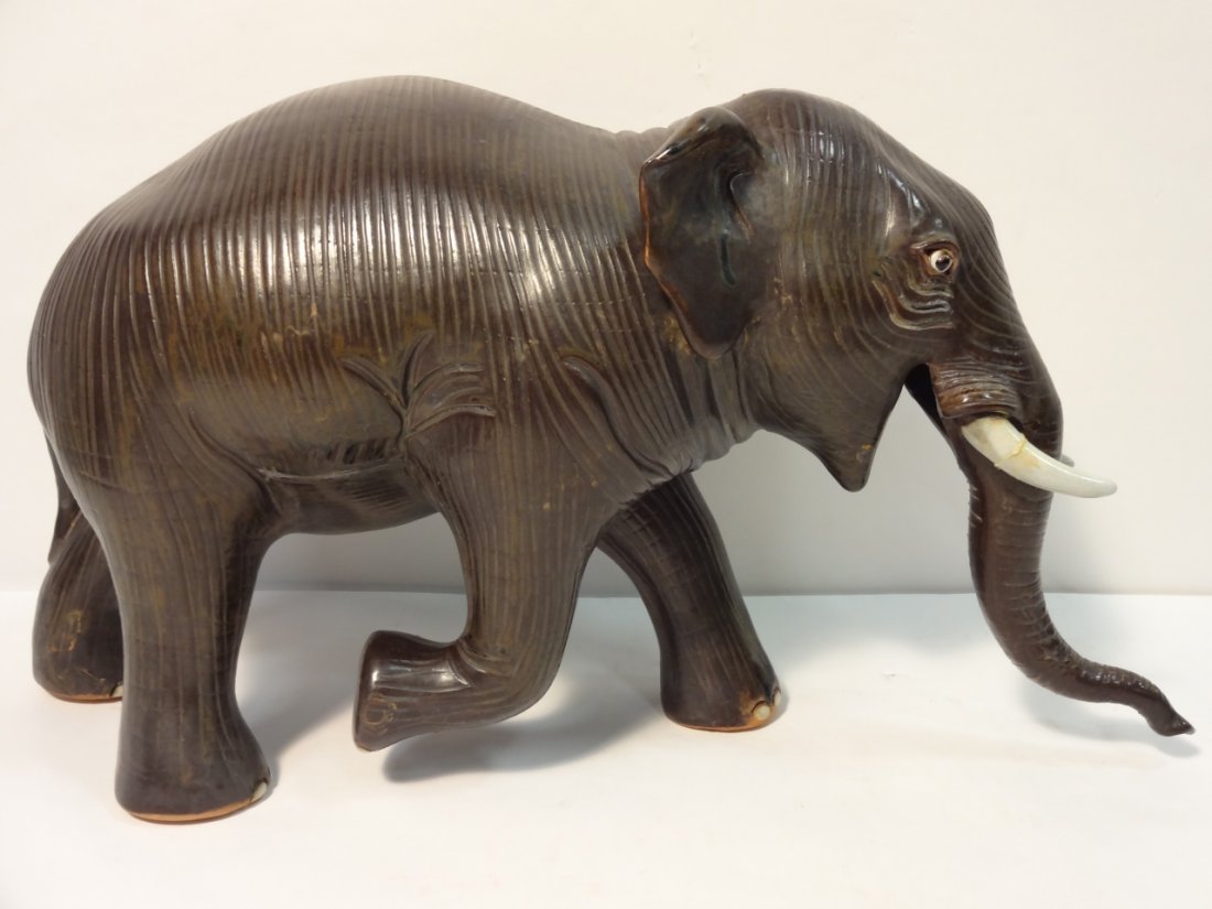 Vintage Hand-Painted Ceramic Elephant Statue: Painted ceramic elephant with one foot raised. The right tusk has a repaired crack. 17" W x 6" D x 9" H, otherwise very good condition.