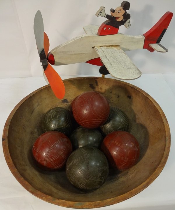 Lot/3 Items inc Mickey Mouse Statue+Bocce Ball Set: Folk art hand-painted wood statue depicting Mickey Mouse on an airplane. 20 3/8" W x 16" D x 15 3/4" H, very good vintage condition. One 19th c. carved Folk Art wooden bowl with traces of orange paint