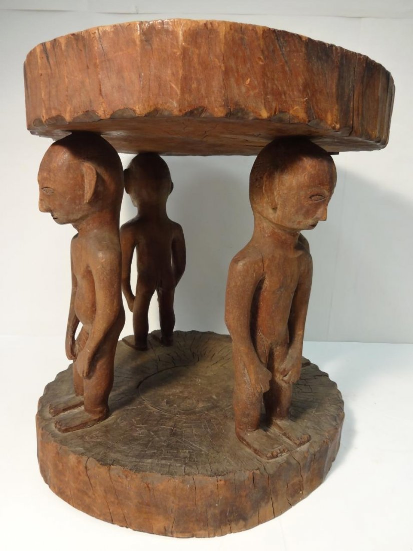 Antique Carved African Chief Stool: Carved African Chief stool with four primitive figures supporting the seat. The seat has a crack in it. 13" diameter x 13 3/4" H.