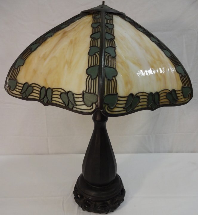 American Arts & Crafts Art Glass Table Lamp: FROM THE HOME OF RON HOWARD: An American Arts & Crafts patinated-bronze and art glass table lamp. Early 20th century. The octagonal conical shade with yellow slag glass panels, with an overlaid band o