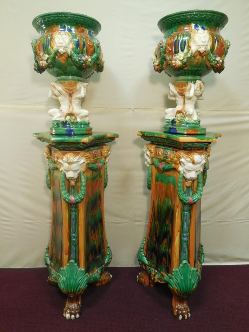 Pair of Colorful Porcelain Pedestals & Planters: A pair of colorful porcelain pedestals and planters with lion head design. The pedestals measure 17" W x 19 1/4" D x 39" H. The planters measure 17" Dia. x 21" H. Excellent condition.