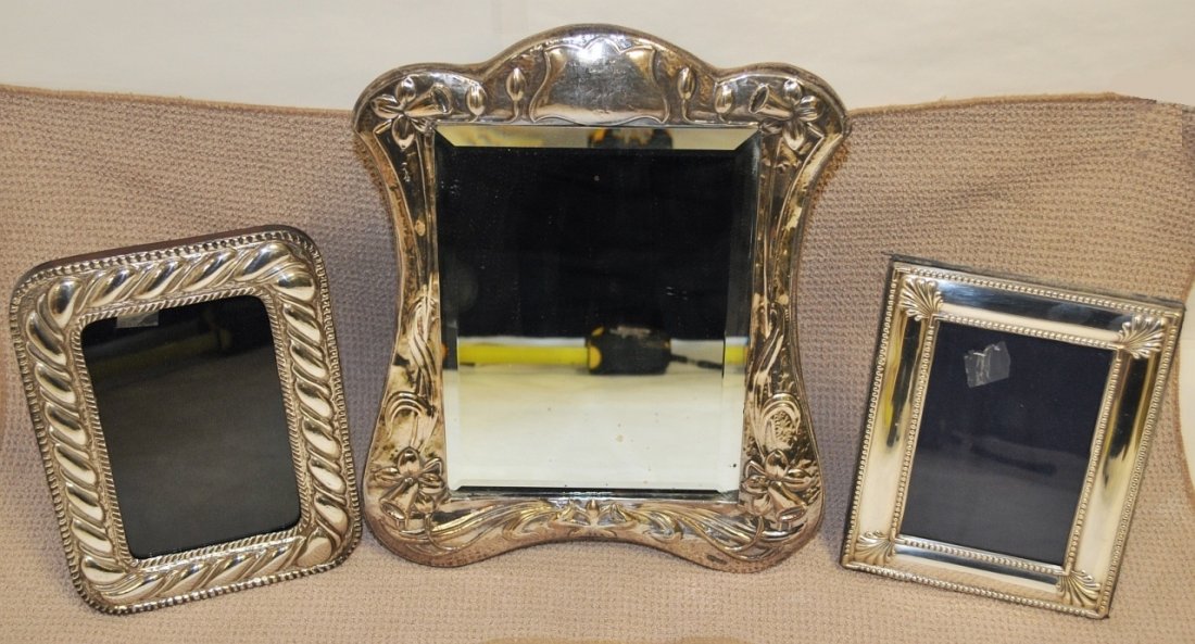 Lot of 3 Sterling Picture Frames & Mirrors: Grouping of three sterling picture frames and mirrors in three different sizes. Mirror has wedding motif. All have chased patterns embossed on them. Measurements: L-R: (1) 8" h x 6" w (2) 12" h x 9.5"