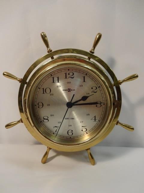 Howard Miller Brass Ship's Wheel Clock: One brass Howard Miller clock that runs on batteries, 10 1/2" dia. x 3 1/2" H- Very good condition.