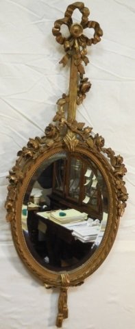 Antique French Rococo Style Oval Mirror: An oval gilt wood mirror with vines and bow. 38 1/" H x 15 1/2" D. Very good condition.