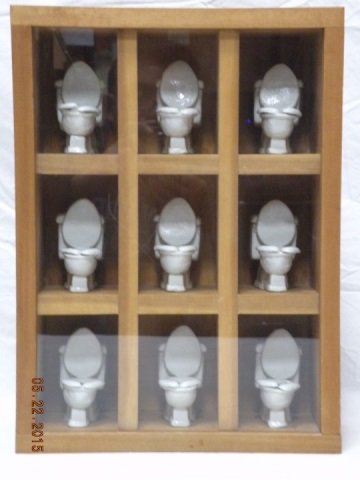 Contemporary Modern Shadow Box Artwork of Toilets: Ceramic toilet bowl shadow box surrealist art. Nine toilet bowls in separate cubicles. Wood box. 12" W x 5 1/4" D x 16 1/4" H. Very good condition.