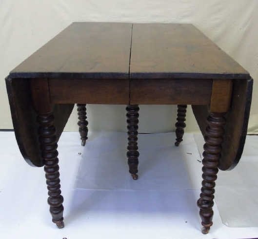 Antique English Mahogany Drop Leaf Table: Antique mahogany drop leaf table. Leaves have rounded ends. Spindle turned legs with casters. With leaves down table measures 42" W x 29" D x 30" H. Open it is 63" D. From a Jeffrey Bilhuber decorated