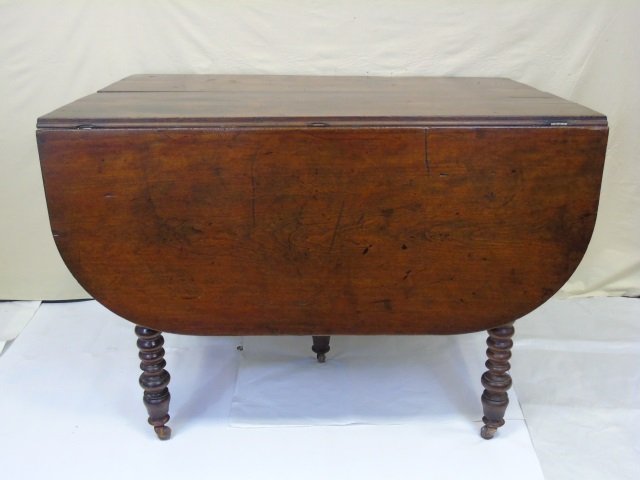 Antique English Mahogany Drop Leaf Table: Antique mahogany drop leaf table. Leaves have rounded ends. Spindle turned legs with casters. With leaves down table measures 42" W x 29" D x 30" H. Open it is 63" D. From a Jeffrey Bilhuber decorated