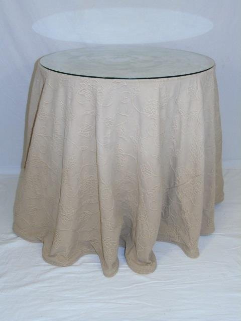 Round Table with Beige Crewel Tablecloth: Round particle board under table with beige crewel tablecloth. 30" diameter x 30" H.