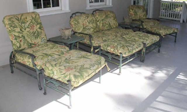 Set of Iron Outdoor Furniture: Set of outdoor iron furniture. Weathered green finish. Tropical floral fabric on cushions. (2) Lattice top end tables 21" square x 19"H, (2) reclining arm chairs, 27" W x 34" D x 38" at highest. (1) r