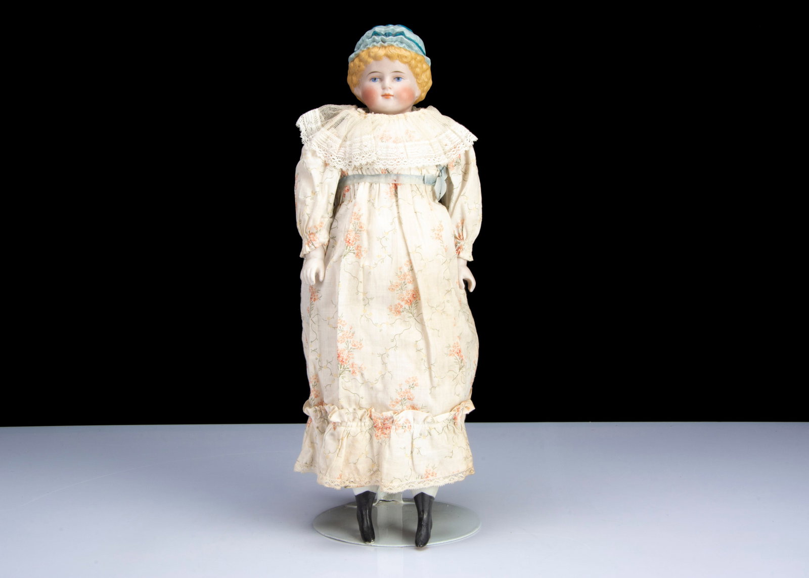 A German 1054 bisque shoulder head doll with moulded hat,: A German 1054 bisque shoulder head doll with moulded hat, with head turned slightly to right, blue painted eyes, closed mouth, blonde painted and moulded curly hair, light blue painted moulded mop cap