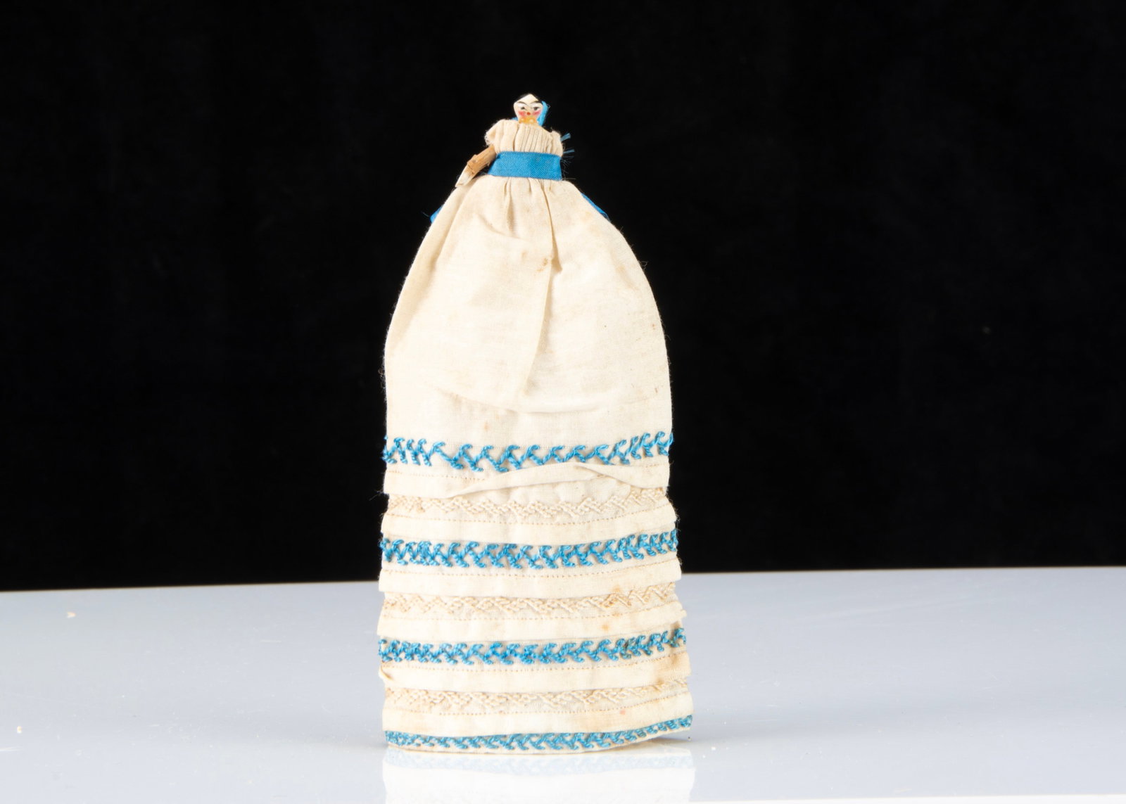 An 19th century Grodnerthal dolls’ house baby,: An 19th century Grodnerthal dolls’ house baby, carved and painted wood with black painted features, rosy cheeks, jointed wooden body and long white cotton robe with tucks and alternate blue and 