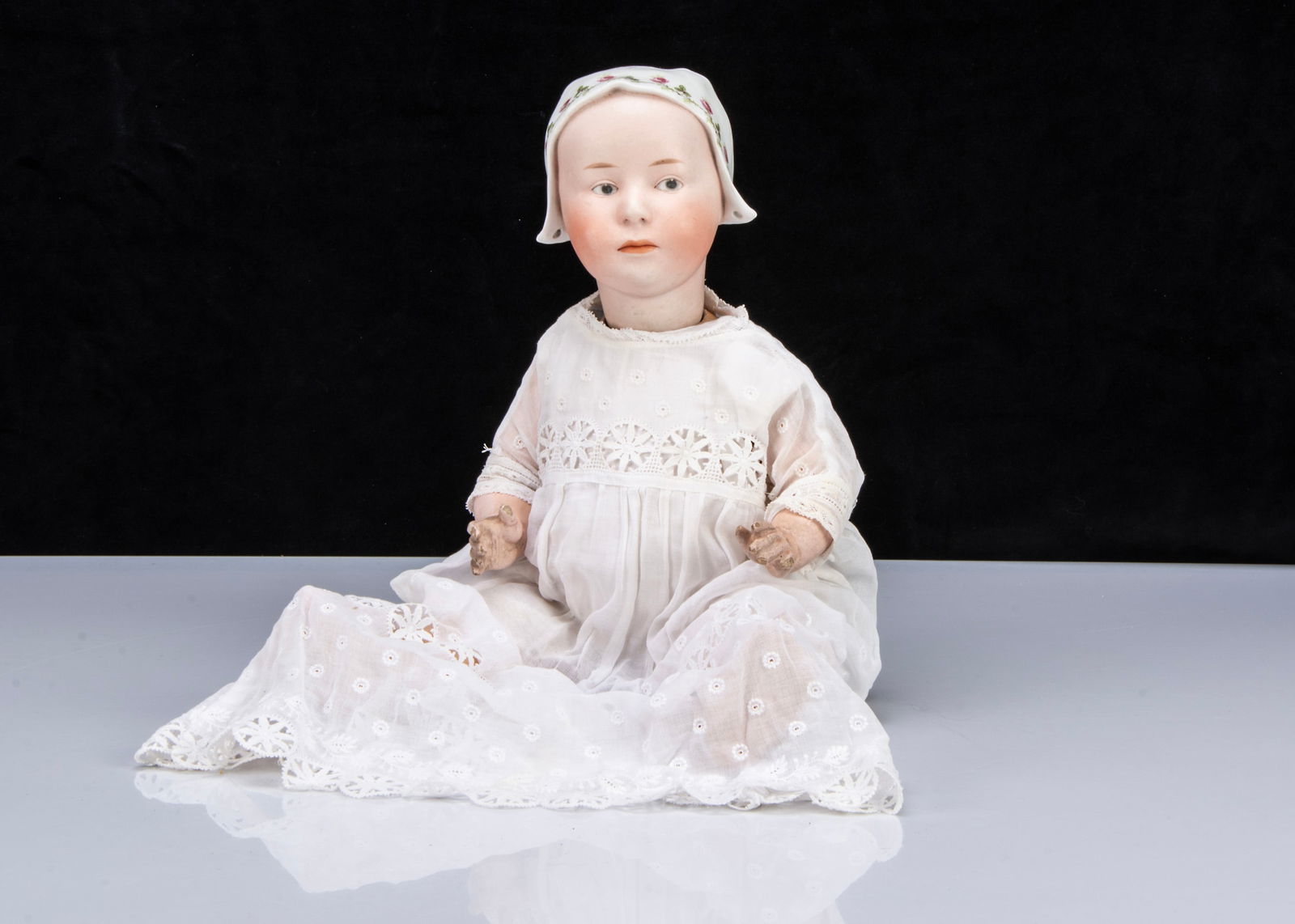 A rare Gebruder Heubach 7977 Baby Stuart,: A rare Gebruder Heubach 7977 Baby Stuart, with grey intaglio eyes, a closed downturned mouth, moulded white bonnet with two ribbon tie-holes and pink rose transfer decoration, back of head with Sunbur