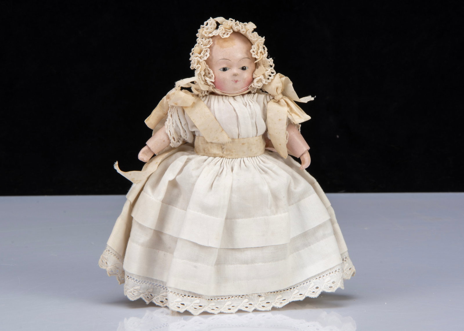 A small mid 19th century papier-mâché Taufling baby,: A small mid 19th century papier-mâché Taufling baby, with dark glass eyes, painted brows, mouth and black tufts of curls, jointed body with cloth joints and papier-mâché limbs, ino