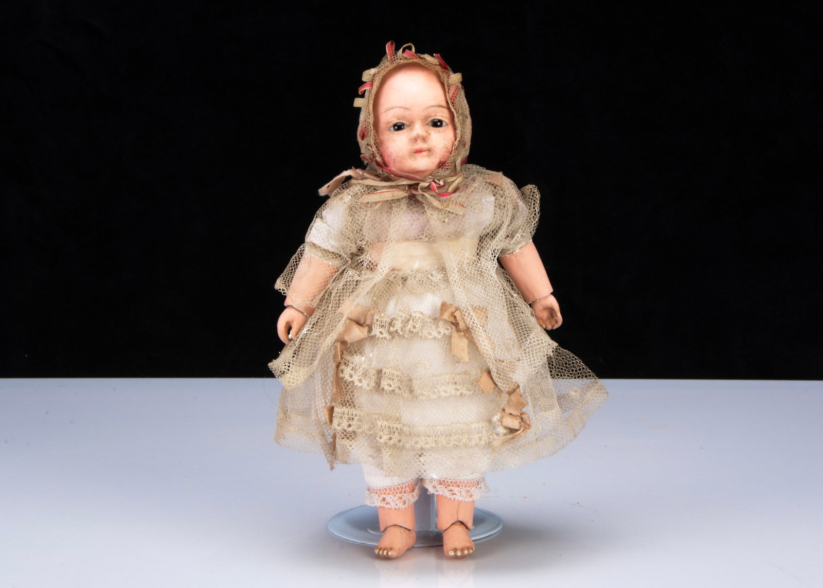 A mid 19th century papier-mâché Taufling baby,: A mid 19th century papier-mâché Taufling baby, with dark glass eyes, painted brows, mouth and black tufts of curls, jointed body with cloth joints and papier-mâché limbs, inoperati