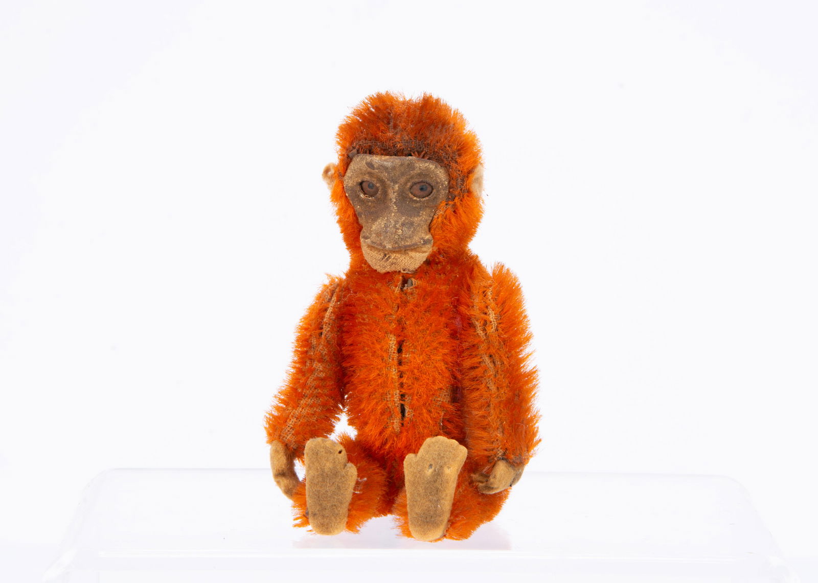 A 1920s Schuco monkey perfume bottle,: A 1920s Schuco monkey perfume bottle, bright orange mohair, flocked tinplate face, metal framed jointed body with felt hands and feet, the head is removed to revel perfume bottle ó5in (12.5cm.) high