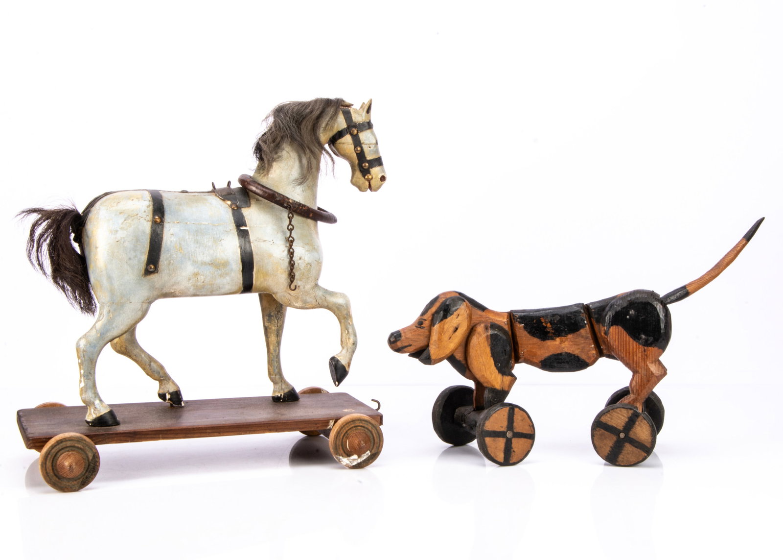 A wooden horse and dachshund on wheels,: A wooden horse and dachshund on wheels, a folk made carved articulated dachshund on wheels, part painted black and part varnished ó17in. (43cm.) long; and a late 19th century carved wooden cart h