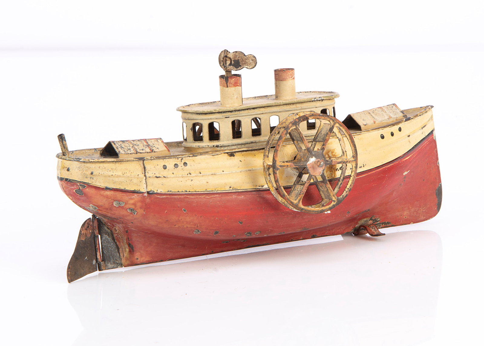 A clockwork painted tinplate paddle steamer,: A clockwork painted tinplate paddle steamer, painted cream and red, cabin with cut-out widows, two funnels with integral funnel smoke key ó8in. (20.5cm.) long (wear, some rust pitting and mechani