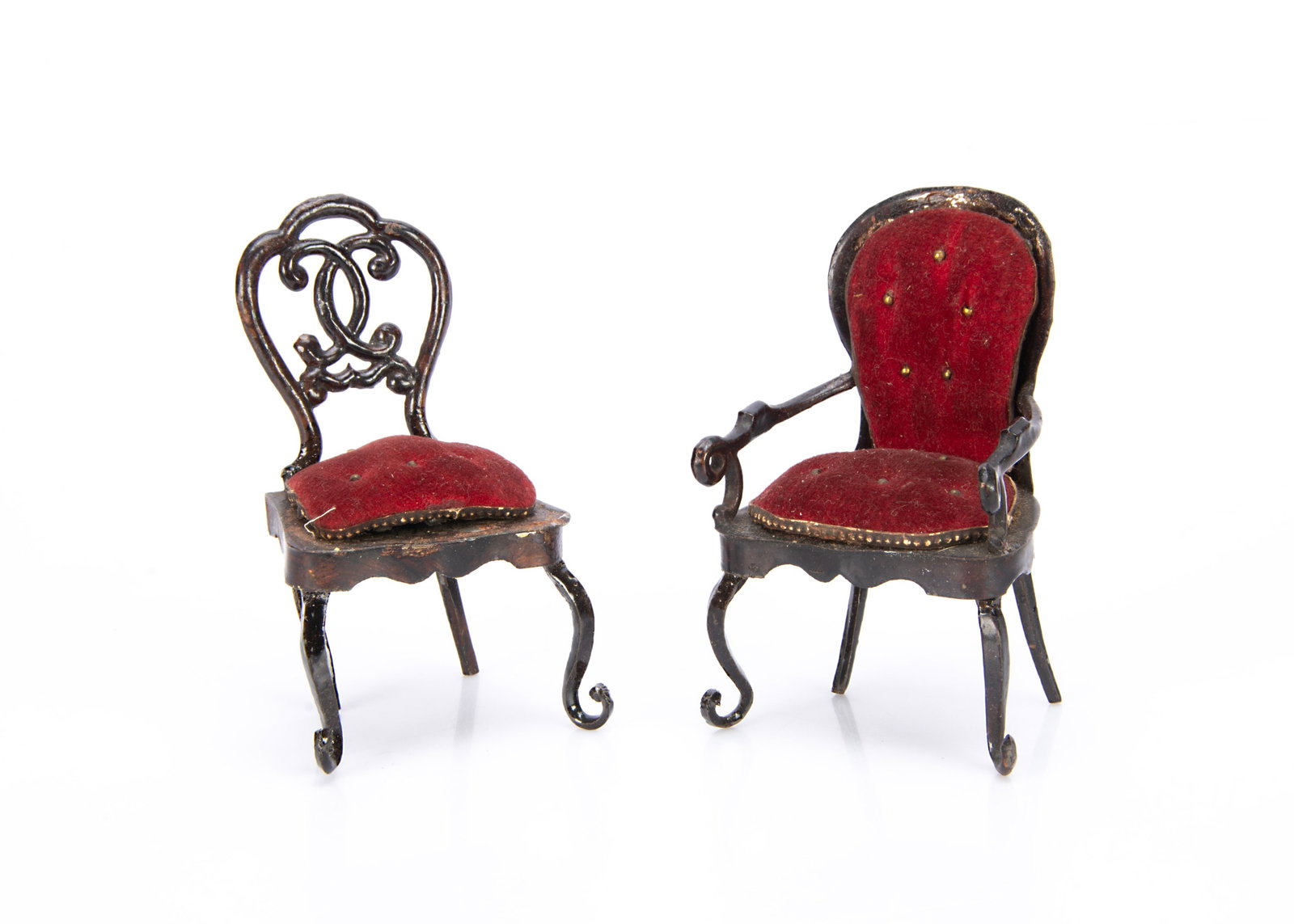 Two 19th century Rock & Graner tinplate dollsí house chairs,: Two 19th century Rock & Graner tinplate dollsí house chairs, painted dark brown graining, one a balloon backed armchair and the other with ornate back, both with dark red velvet buttoned upholste