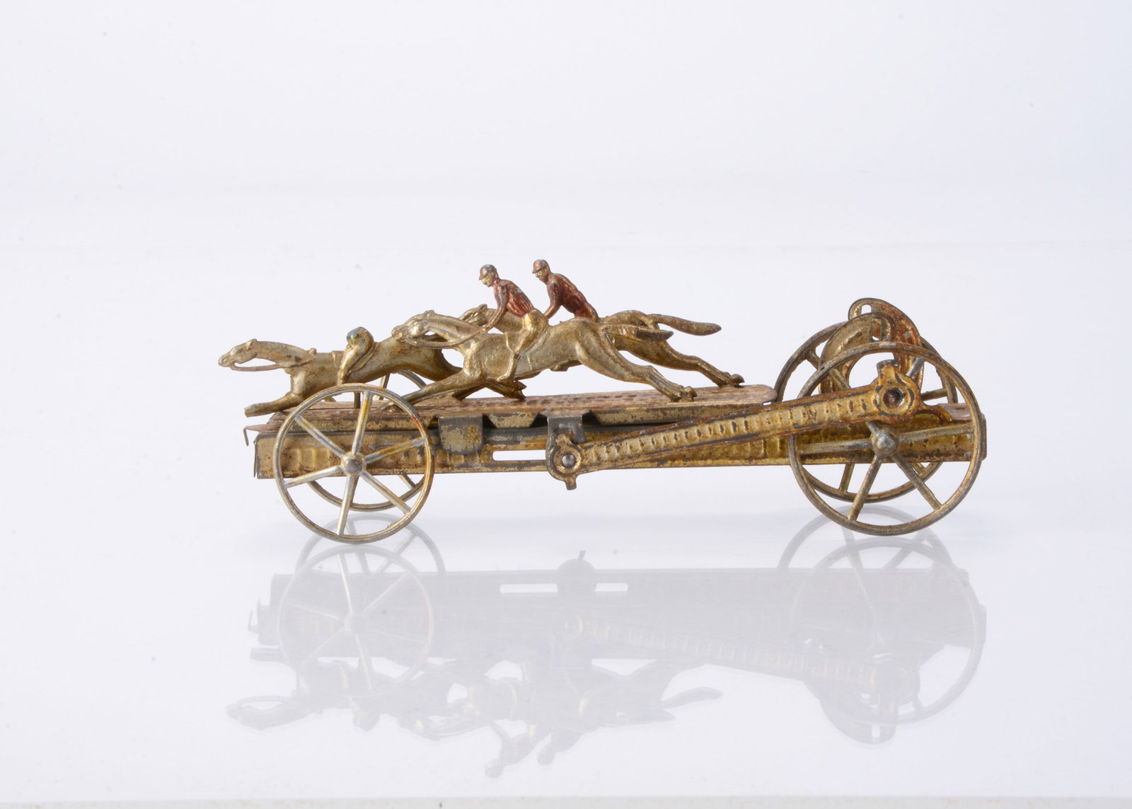 A French Two Penny Toy of a horse race,: A French Two Penny Toy of a horse race, gold spirit-painted tinplate with three cast race horses and spoked wheels, sliding mechanism —7in. (17.5cm) long (missing one jockey’s head and fly